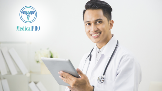 Doctor using clinic management software on a computer with stethoscope and medical documents nearby.